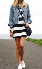 Wearing a denim jacket, white sneakers, and a black and white striped knee-length dress